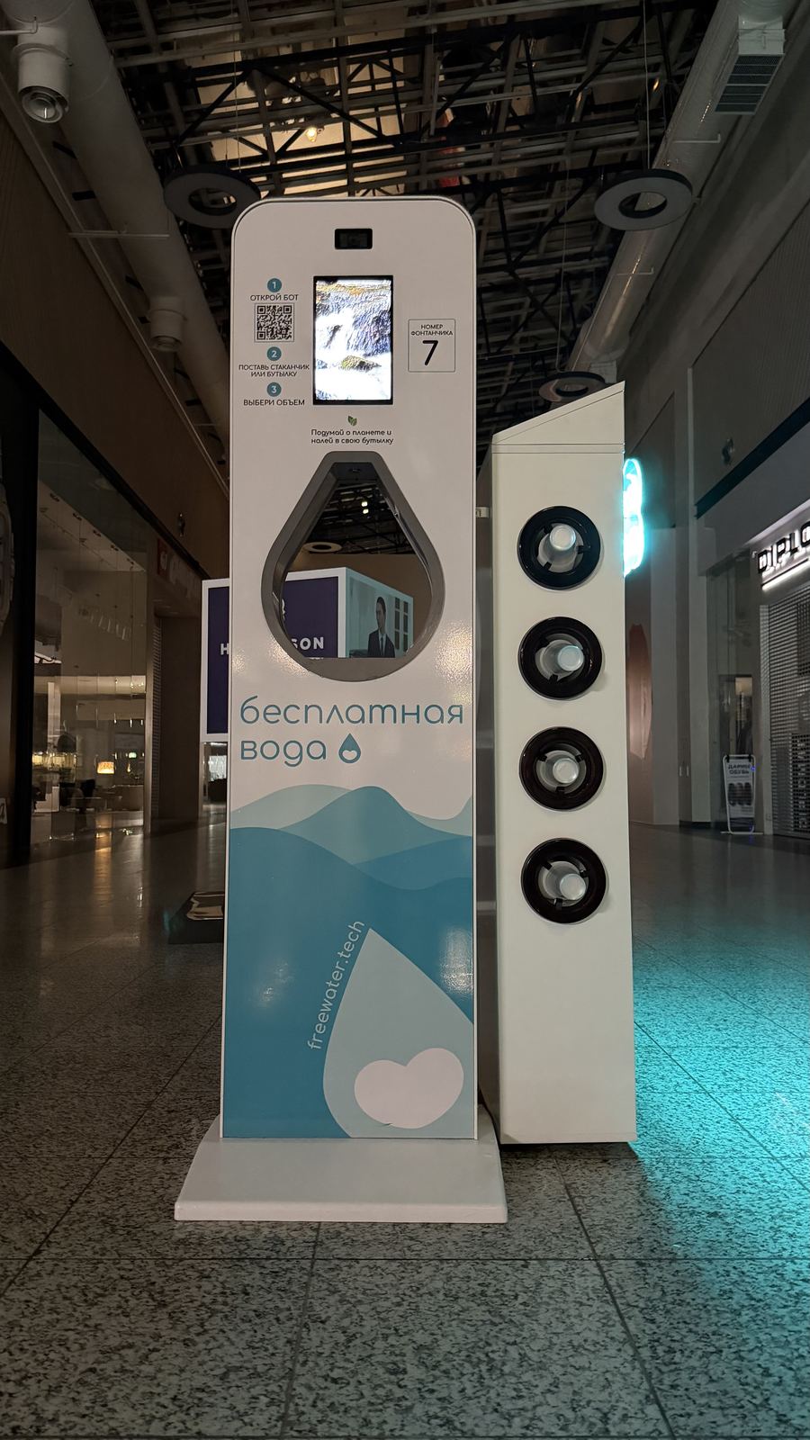 Фонтан с экраном и камерой, рядом стойка со стаканчиками